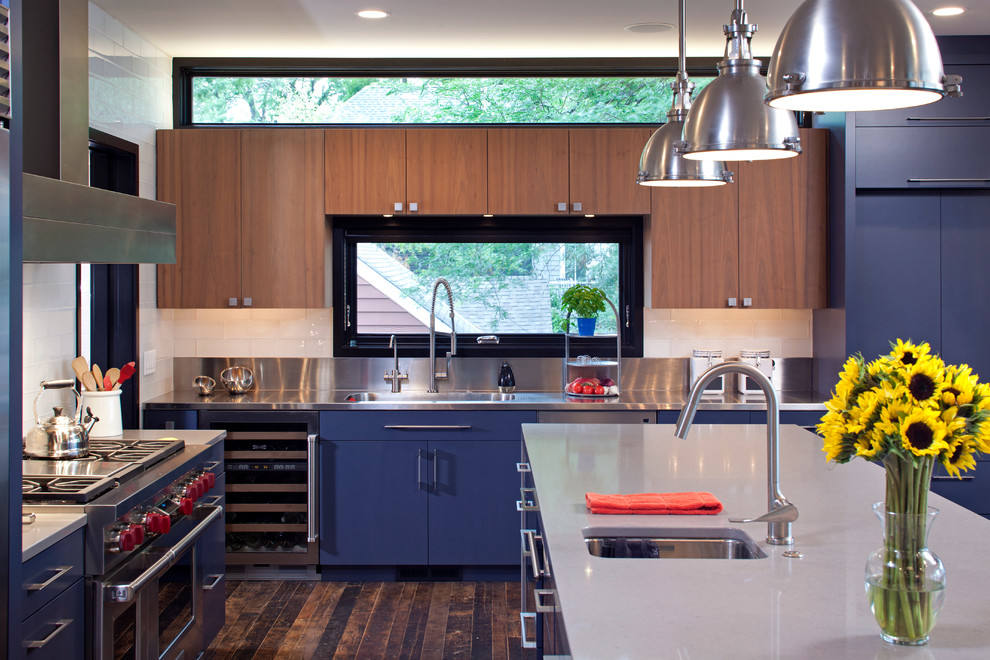Modern inredning av ett kök, med en undermonterad diskho, skåp i mellenmörkt trä, bänkskiva i kvartsit, vitt stänkskydd, stänkskydd i tunnelbanekakel, rostfria vitvaror, mellanmörkt trägolv och en köksö