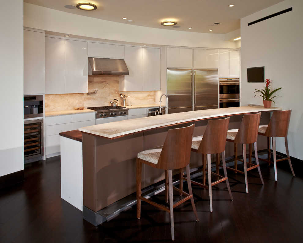 Moderne Küche mit flächenbündigen Schrankfronten, weißen Schränken, Küchenrückwand in Beige, Küchengeräten aus Edelstahl, dunklem Holzboden, Halbinsel und braunem Boden in Houston