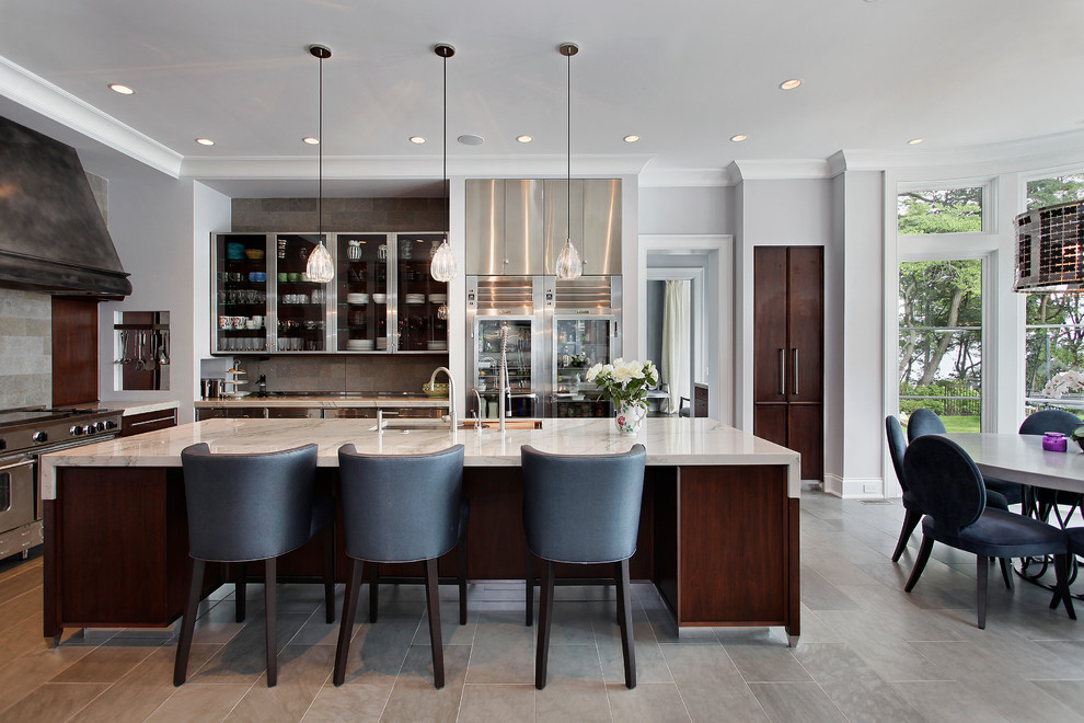 This is an example of a classic kitchen/diner in Chicago with glass-front cabinets, dark wood cabinets, grey splashback and stainless steel appliances.