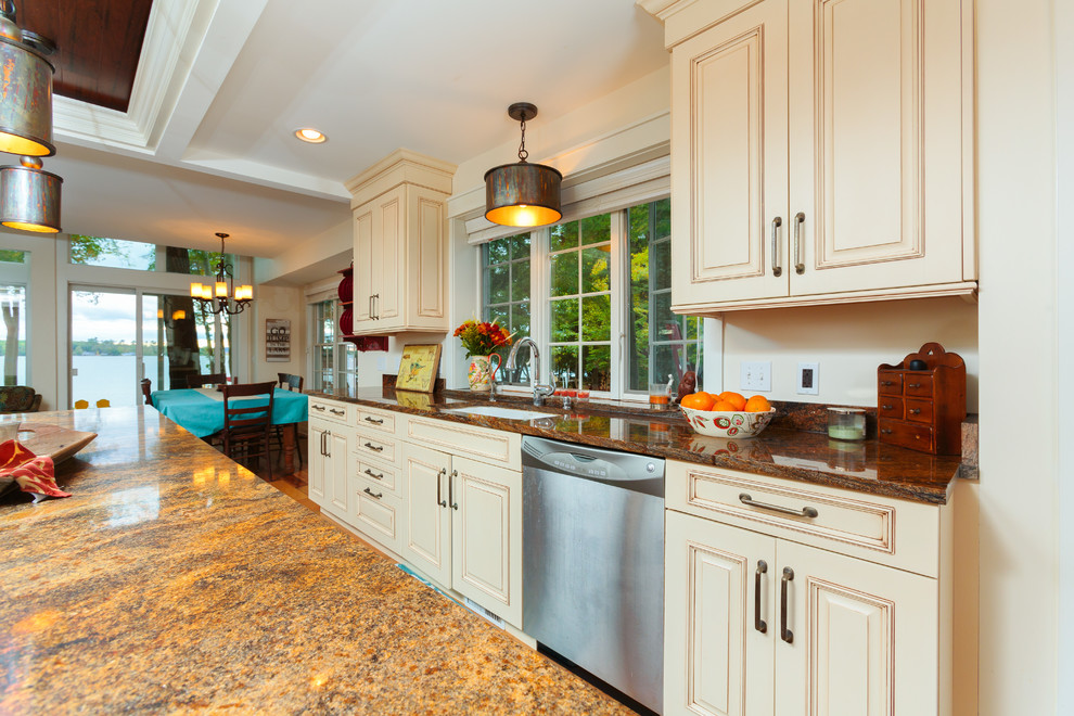 Exempel på ett stort amerikanskt kök och matrum, med vita skåp, granitbänkskiva, rostfria vitvaror, mellanmörkt trägolv och en köksö