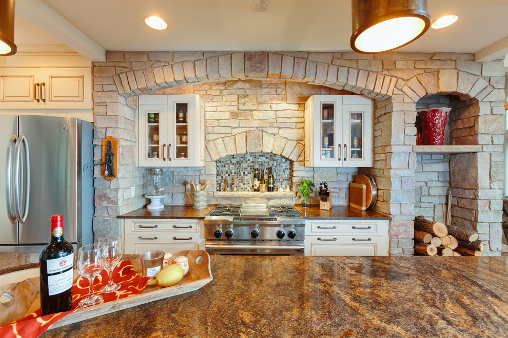 Exemple d'une grande cuisine américaine craftsman avec des portes de placard blanches, un plan de travail en granite, un électroménager en acier inoxydable, un sol en bois brun et îlot.