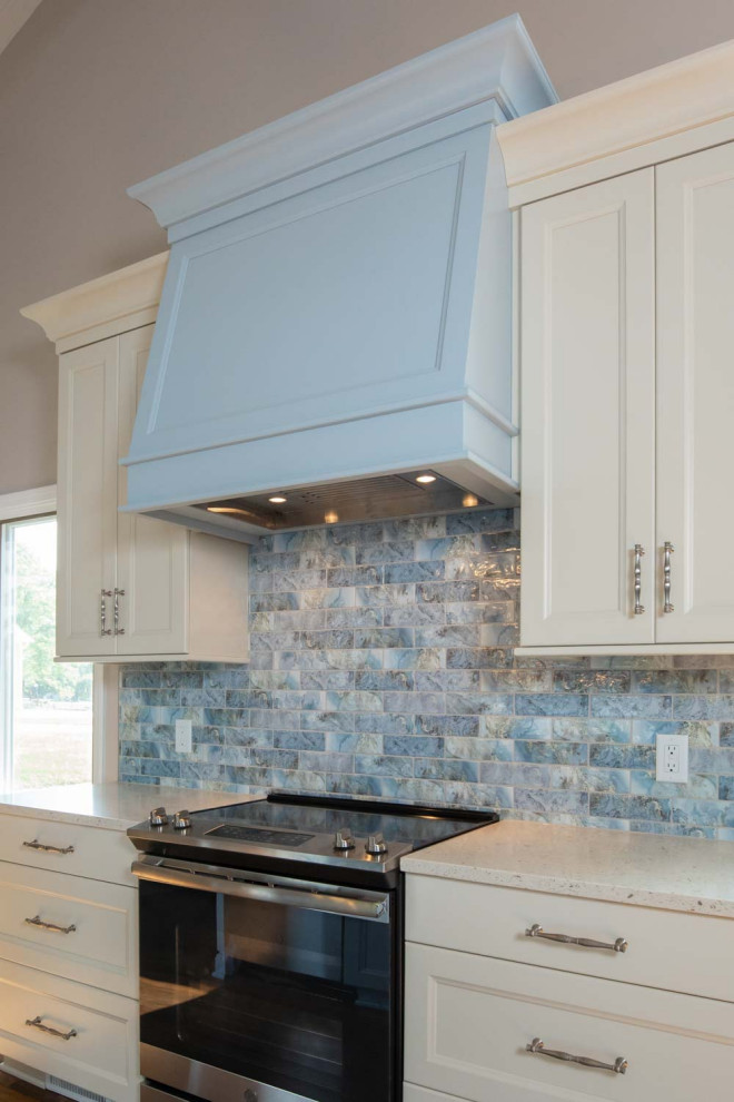 Foto på ett stort vintage blå kök, med en undermonterad diskho, luckor med infälld panel, vita skåp, bänkskiva i kvarts, blått stänkskydd, stänkskydd i keramik, rostfria vitvaror, mellanmörkt trägolv, en köksö och brunt golv