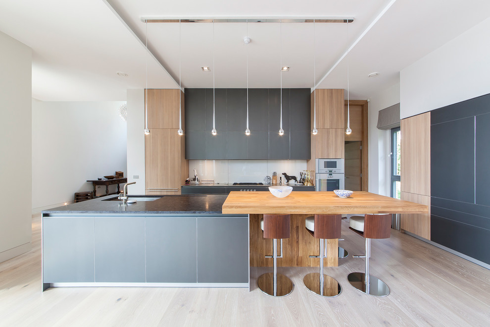 Diseño de cocina actual extra grande abierta con suelo de madera clara, una isla, fregadero bajoencimera y barras de cocina