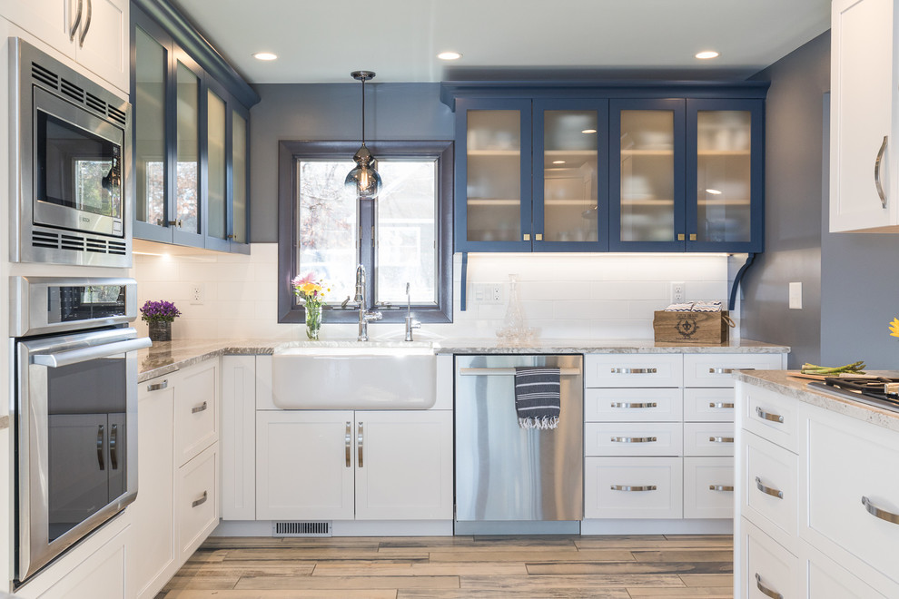 Example of a mid-sized beach style l-shaped painted wood floor and multicolored floor open concept kitchen design in Manchester with a farmhouse sink, shaker cabinets, blue cabinets, glass countertops, yellow backsplash and ceramic backsplash
