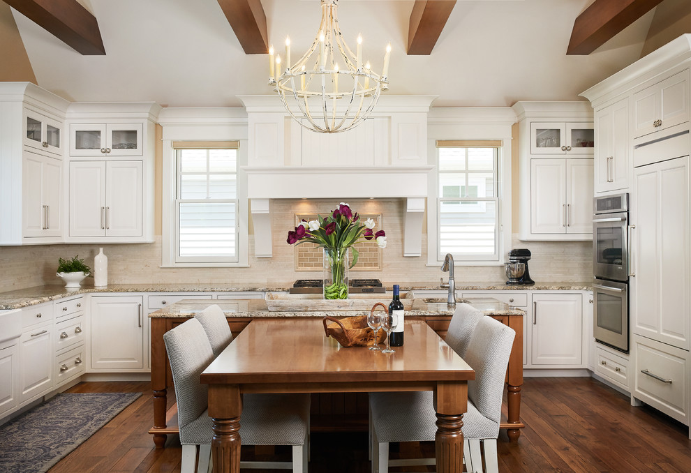 Large traditional u-shaped kitchen/diner in Grand Rapids with a submerged sink, raised-panel cabinets, white cabinets, beige splashback, metro tiled splashback, stainless steel appliances, dark hardwood flooring, an island, brown floors and a vaulted ceiling.