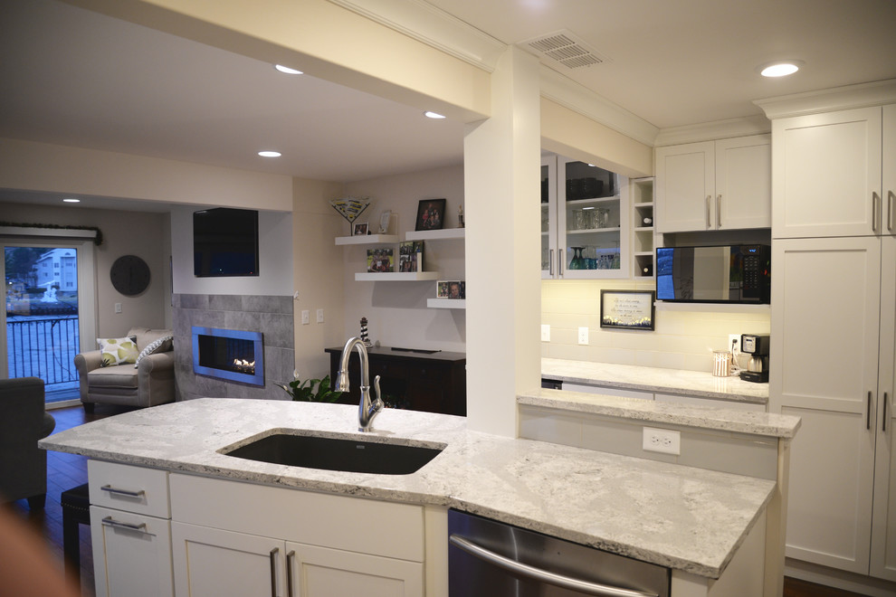 Exempel på ett litet modernt kök, med en undermonterad diskho, luckor med infälld panel, vita skåp, bänkskiva i kvartsit, vitt stänkskydd, stänkskydd i tunnelbanekakel, rostfria vitvaror, mörkt trägolv och en köksö