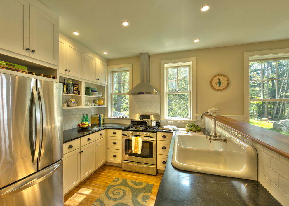 Eat-in kitchen - small traditional u-shaped medium tone wood floor eat-in kitchen idea in Burlington with a drop-in sink, shaker cabinets, white cabinets, white backsplash, subway tile backsplash and stainless steel appliances