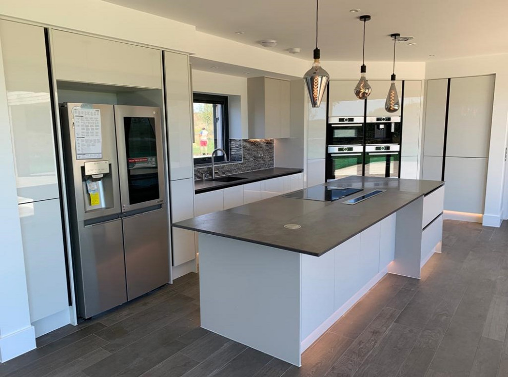 Inspiration for a large modern l-shaped open concept kitchen remodel in Dorset with an integrated sink, flat-panel cabinets, white cabinets, quartzite countertops, gray backsplash, cement tile backsplash, stainless steel appliances, an island and gray countertops