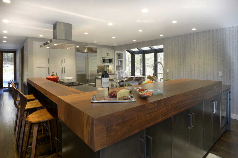 Idéer för ett mellanstort modernt kök, med en undermonterad diskho, släta luckor, grå skåp, träbänkskiva, stänkskydd med metallisk yta, rostfria vitvaror, mörkt trägolv, en köksö och brunt golv