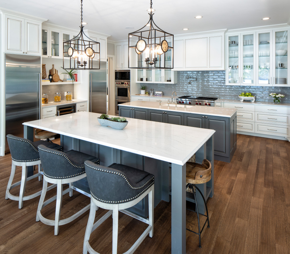 Eat-in kitchen - large transitional u-shaped medium tone wood floor and brown floor eat-in kitchen idea in Minneapolis with a farmhouse sink, white cabinets, marble countertops, gray backsplash, cement tile backsplash, two islands, white countertops and stainless steel appliances