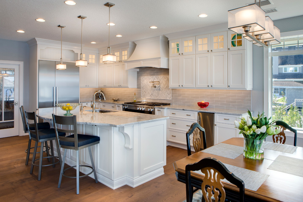 Eat-in kitchen - mid-sized country l-shaped light wood floor eat-in kitchen idea in Orlando with an undermount sink, shaker cabinets, white cabinets, granite countertops, gray backsplash, subway tile backsplash, stainless steel appliances and an island