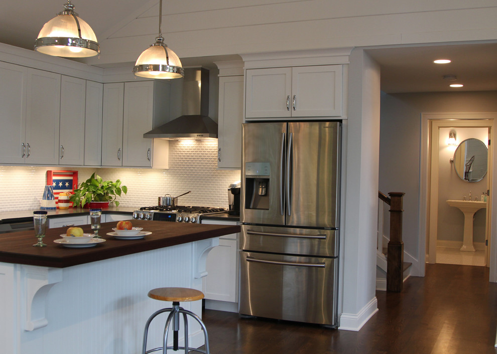 Klassisk inredning av ett mellanstort kök, med en rustik diskho, skåp i shakerstil, vita skåp, träbänkskiva, vitt stänkskydd, stänkskydd i mosaik, rostfria vitvaror, mellanmörkt trägolv och en köksö