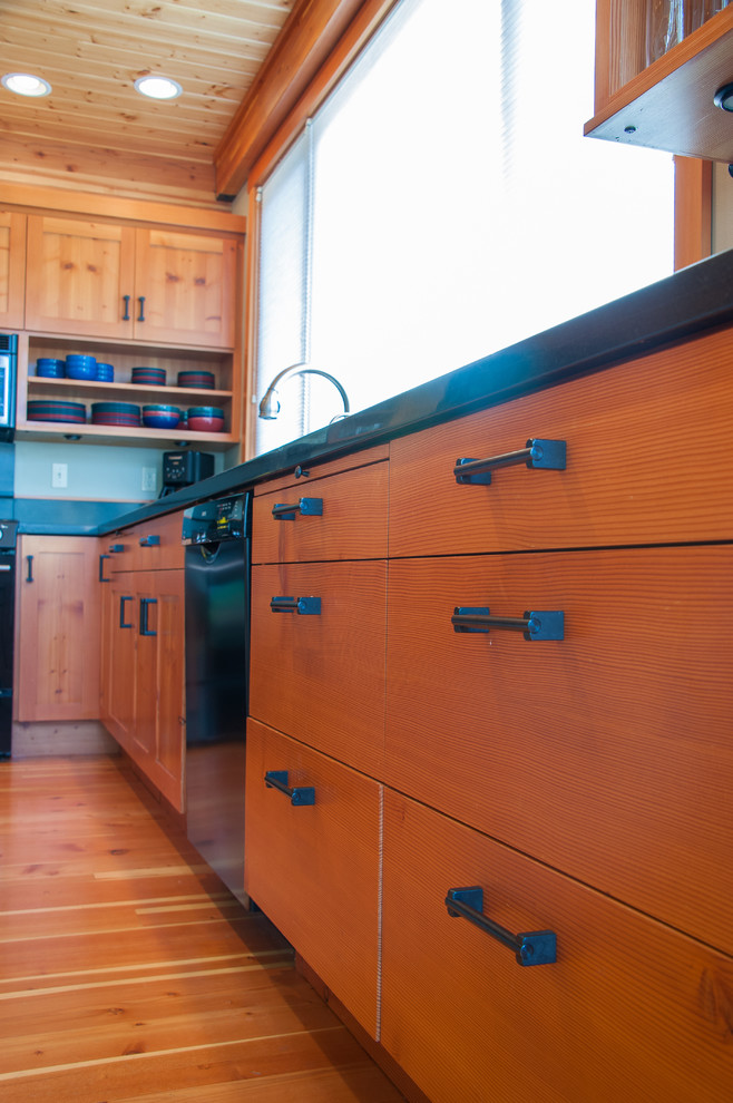 Cette photo montre une cuisine ouverte montagne en L et bois brun de taille moyenne avec un placard à porte shaker, un plan de travail en bois, un électroménager noir, un sol en bois brun, îlot et un sol marron.