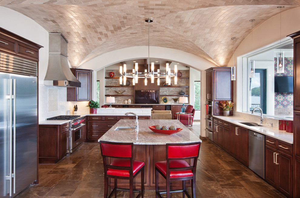 Kitchen - mediterranean u-shaped kitchen idea in Austin with an undermount sink, raised-panel cabinets, dark wood cabinets, beige backsplash and stainless steel appliances