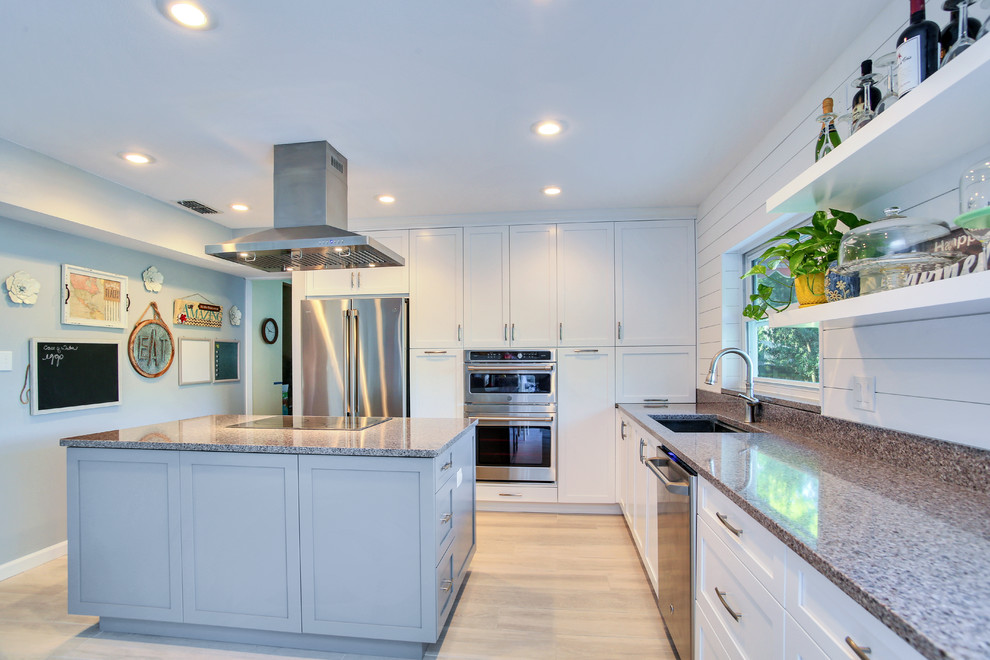 Example of a mid-sized trendy l-shaped light wood floor and beige floor open concept kitchen design in Tampa with an undermount sink, shaker cabinets, white cabinets, stainless steel appliances, an island and gray countertops