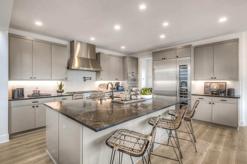 Inspiration for a large contemporary l-shaped kitchen in Seattle with a submerged sink, flat-panel cabinets, grey cabinets, white splashback, stainless steel appliances, an island, grey floors and grey worktops.