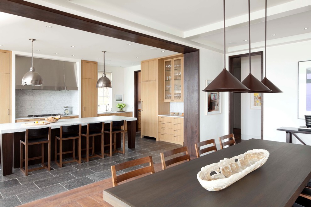 Стильный дизайн: кухня в стиле неоклассика (современная классика) с обеденным столом, плоскими фасадами, светлыми деревянными фасадами, белым фартуком, фартуком из каменной плитки и техникой под мебельный фасад - последний тренд
