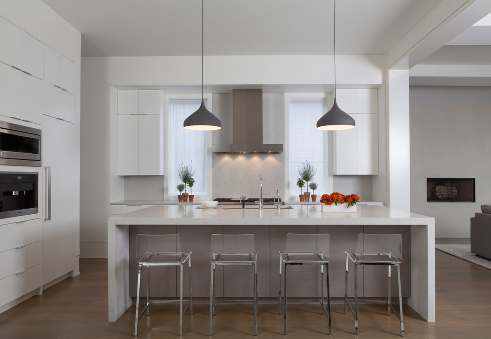 Moderne Küche in grau-weiß mit Unterbauwaschbecken, flächenbündigen Schrankfronten, weißen Schränken, Küchenrückwand in Grau, Küchengeräten aus Edelstahl, Kücheninsel und dunklem Holzboden in Chicago