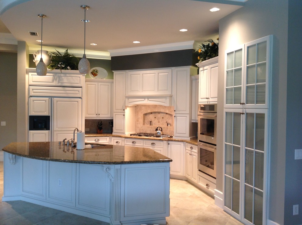 Mid-sized elegant l-shaped porcelain tile eat-in kitchen photo in Tampa with an undermount sink, raised-panel cabinets, white cabinets, granite countertops, beige backsplash, ceramic backsplash, paneled appliances and an island