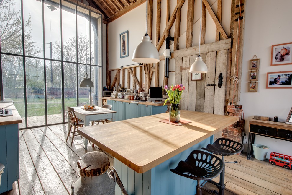 Bild på ett lantligt kök, med blå skåp och träbänkskiva
