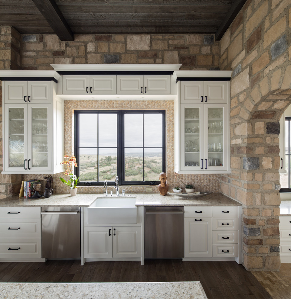 Example of a large mountain style l-shaped dark wood floor and brown floor eat-in kitchen design in Denver with a farmhouse sink, white cabinets, beige backsplash, stainless steel appliances, an island, beige countertops and raised-panel cabinets