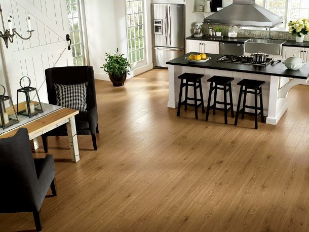 Example of a large trendy l-shaped light wood floor open concept kitchen design in St Louis with a farmhouse sink, raised-panel cabinets, white cabinets, solid surface countertops, multicolored backsplash, mosaic tile backsplash, stainless steel appliances and an island