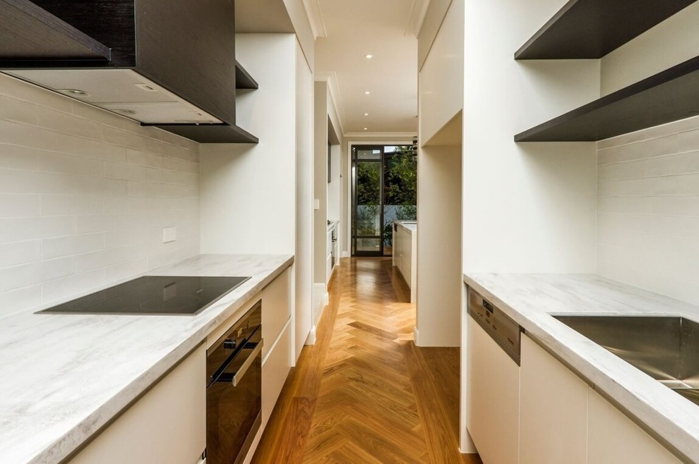 Photo of a modern kitchen in Auckland with light hardwood flooring and an island.