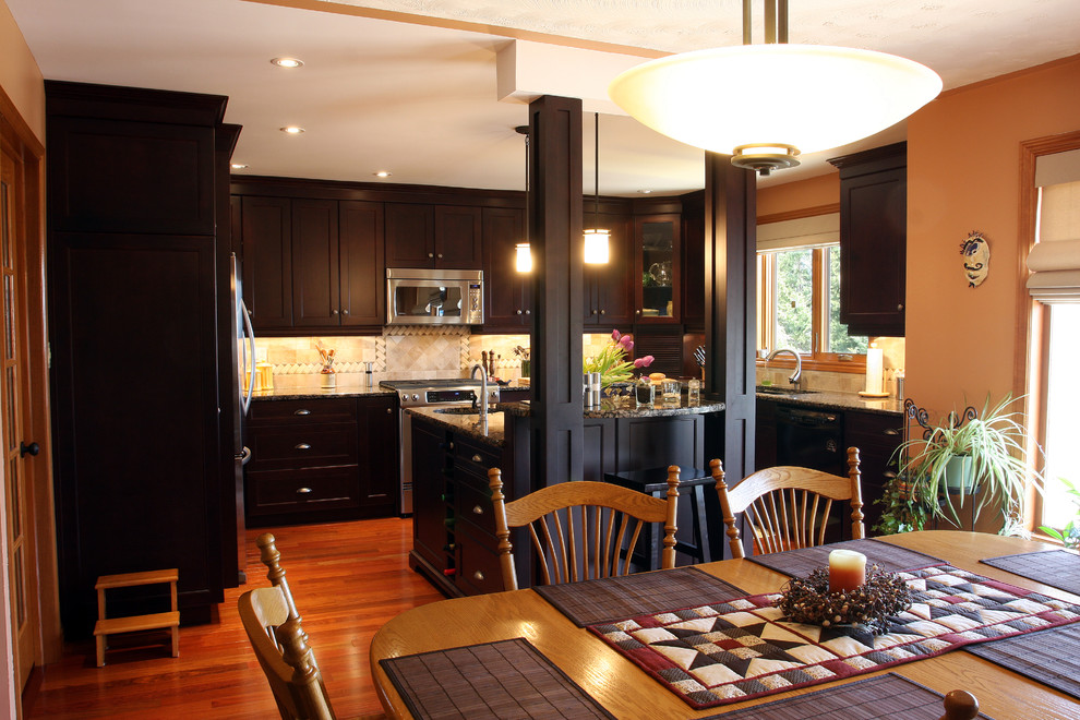 Elegant u-shaped eat-in kitchen photo in Toronto with recessed-panel cabinets, dark wood cabinets and beige backsplash