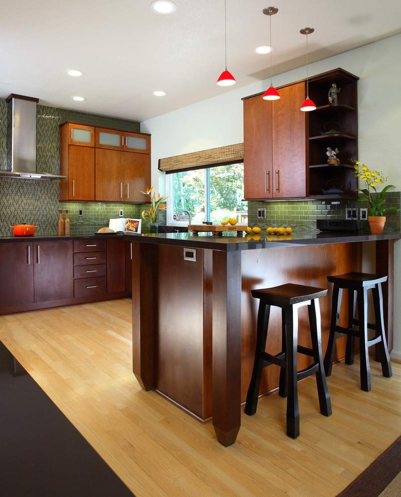 Bild på ett funkis kök och matrum, med en undermonterad diskho, släta luckor, bruna skåp, bänkskiva i kvartsit, grönt stänkskydd, stänkskydd i glaskakel och rostfria vitvaror