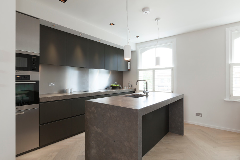 This is an example of a medium sized modern single-wall kitchen/diner in London with a built-in sink, flat-panel cabinets, black cabinets, limestone worktops, grey splashback, metal splashback, stainless steel appliances, medium hardwood flooring and an island.