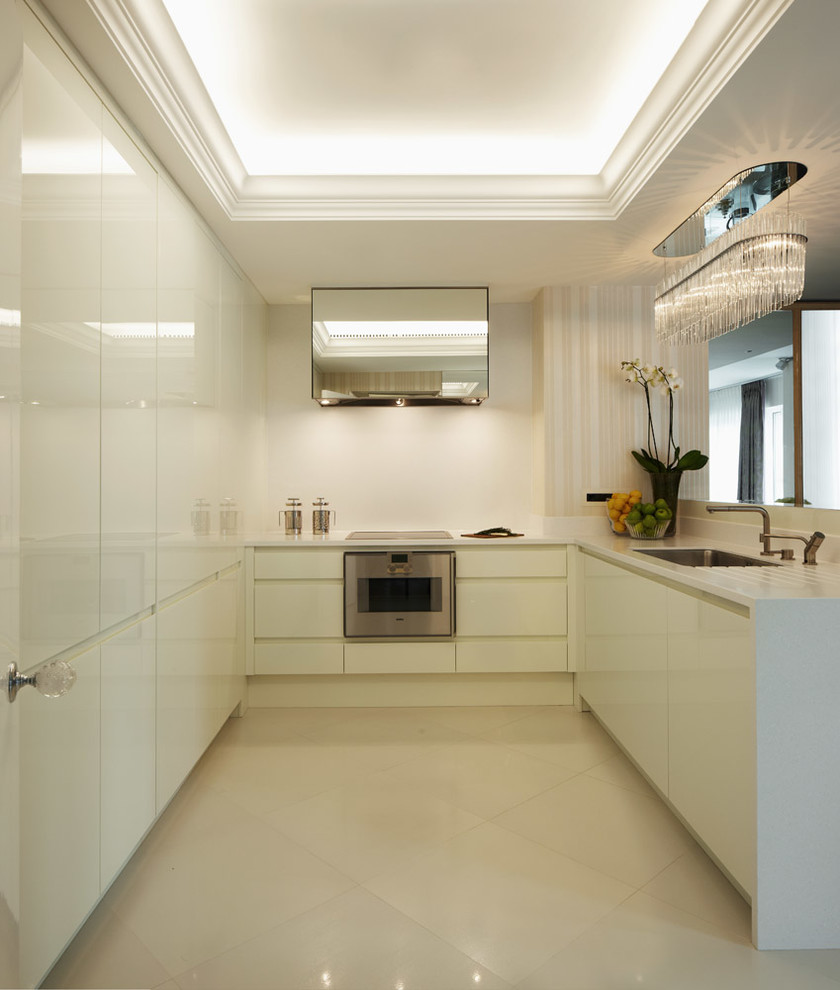 Inspiration for a contemporary u-shaped kitchen in London with a submerged sink, flat-panel cabinets, white cabinets and integrated appliances.