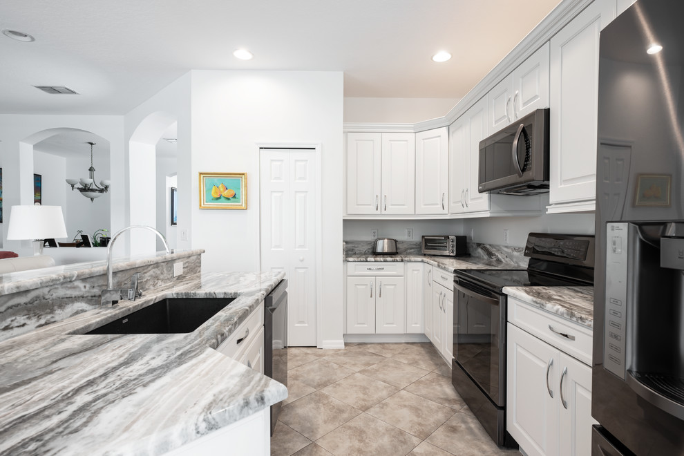This is an example of a medium sized traditional u-shaped kitchen/diner in Tampa with a submerged sink, raised-panel cabinets, white cabinets, engineered stone countertops, black appliances, porcelain flooring, an island, beige floors and grey worktops.