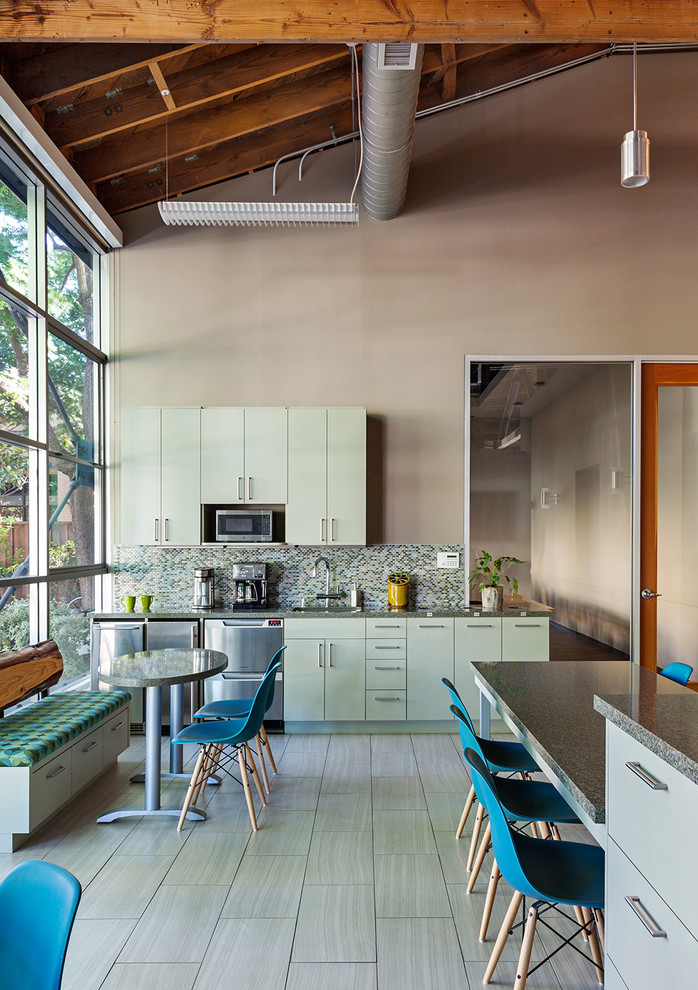 Example of a mid-sized urban single-wall ceramic tile and gray floor open concept kitchen design in San Francisco with an undermount sink, flat-panel cabinets, green cabinets, quartz countertops, multicolored backsplash, mosaic tile backsplash, stainless steel appliances, an island and gray countertops