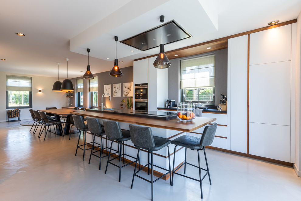 Esempio di un cucina con isola centrale design con ante bianche, top in granito, pavimento in cemento e pavimento grigio