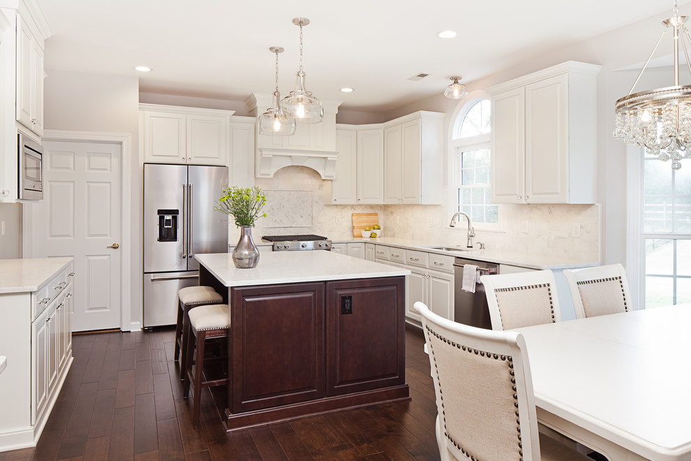Mid-sized elegant u-shaped dark wood floor and brown floor eat-in kitchen photo in Charlotte with an undermount sink, raised-panel cabinets, white cabinets, quartz countertops, white backsplash, marble backsplash, stainless steel appliances and an island