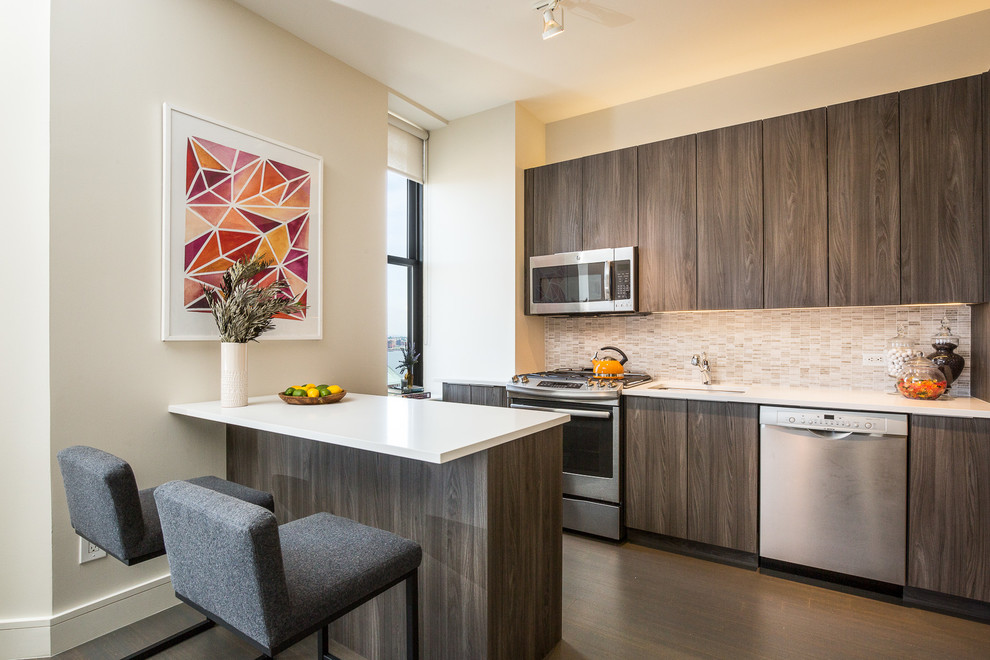 Photo of a contemporary galley kitchen/diner in New York with a submerged sink, flat-panel cabinets, dark wood cabinets, beige splashback, mosaic tiled splashback, stainless steel appliances, dark hardwood flooring, a breakfast bar and composite countertops.