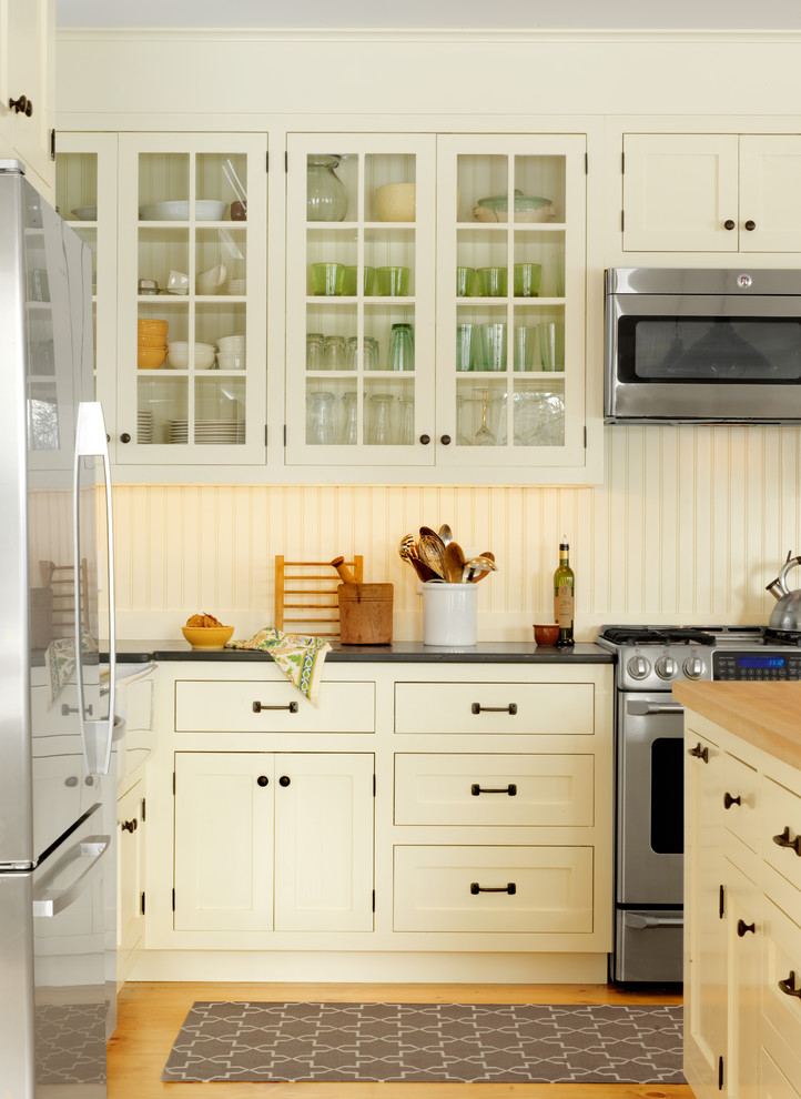 Example of a classic kitchen design in Burlington with glass-front cabinets, yellow cabinets, wood countertops and stainless steel appliances