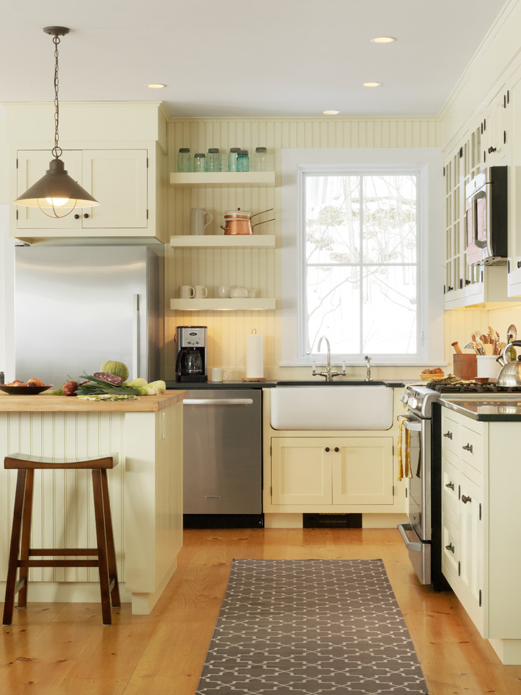 Elegant kitchen photo in Burlington with a farmhouse sink, yellow cabinets, recessed-panel cabinets and stainless steel appliances