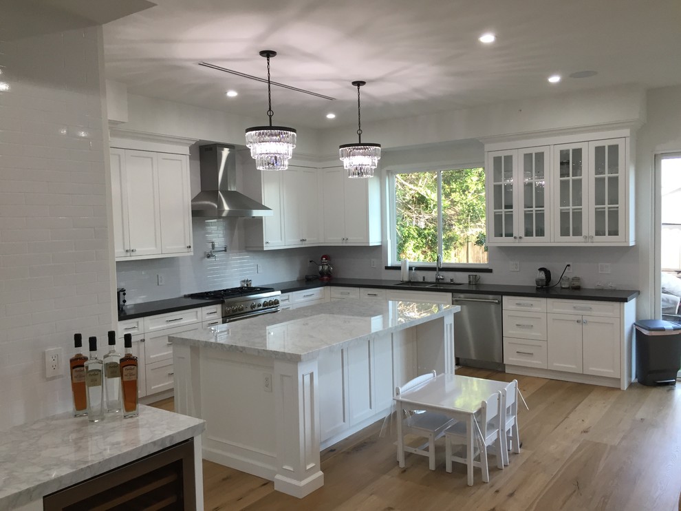 Exempel på ett mellanstort klassiskt grå grått kök, med en dubbel diskho, skåp i shakerstil, vita skåp, marmorbänkskiva, vitt stänkskydd, rostfria vitvaror, ljust trägolv, en köksö, beiget golv och stänkskydd i tunnelbanekakel