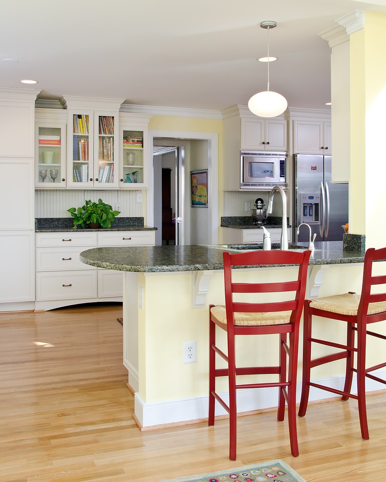 Cette photo montre une cuisine chic avec un placard avec porte à panneau encastré, des portes de placard blanches et un électroménager en acier inoxydable.