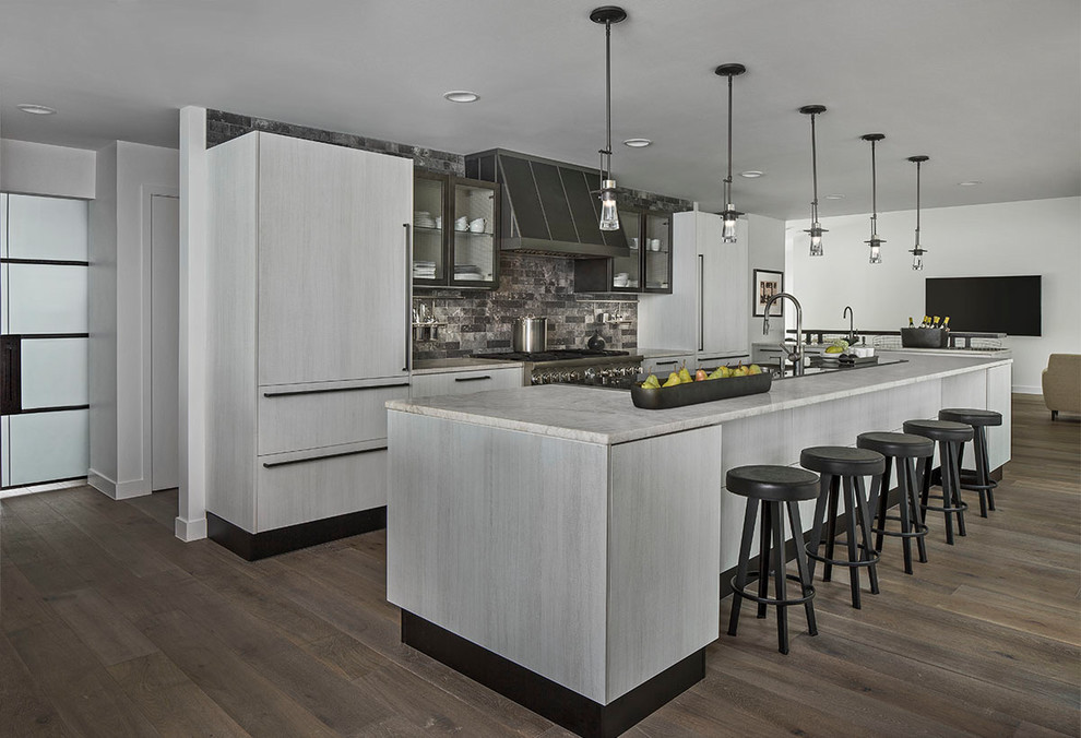 Large trendy galley dark wood floor and brown floor open concept kitchen photo in Detroit with flat-panel cabinets, gray cabinets, multicolored backsplash, an island, paneled appliances, limestone countertops and stone tile backsplash