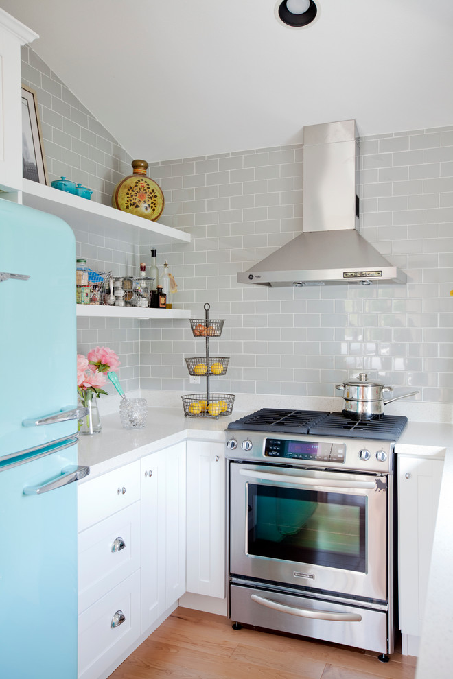 Cette photo montre une cuisine éclectique avec un placard à porte shaker, des portes de placard blanches, une crédence grise, une crédence en carrelage métro et un électroménager de couleur.