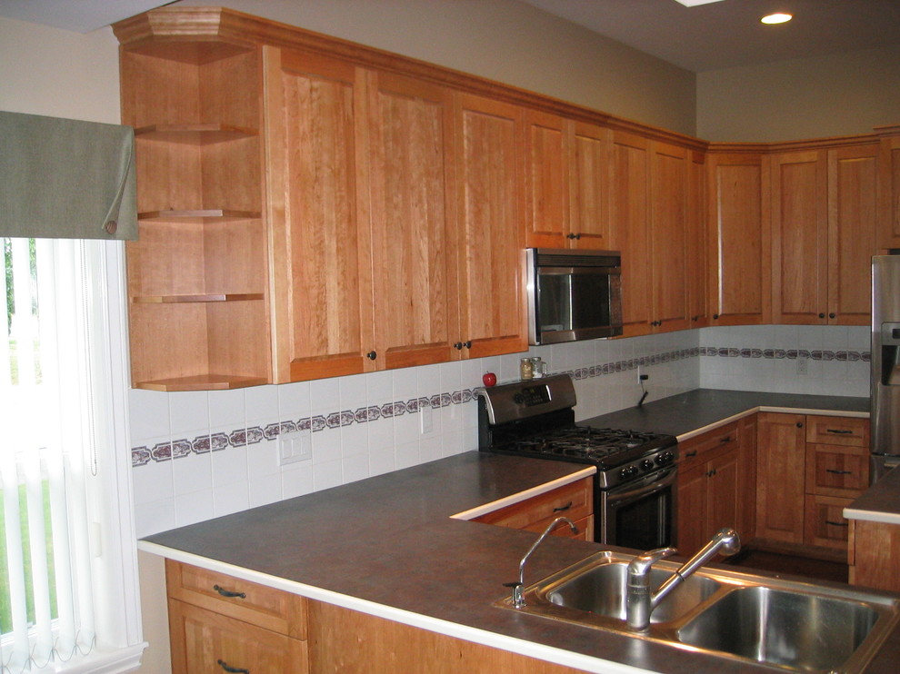 Klassische Wohnküche in U-Form mit Doppelwaschbecken, hellbraunen Holzschränken, Küchengeräten aus Edelstahl und Kücheninsel in Vancouver