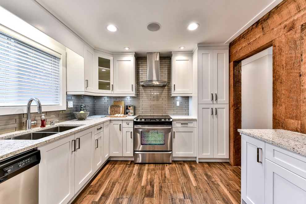 Foto på ett mellanstort funkis kök, med en undermonterad diskho, skåp i shakerstil, vita skåp, bänkskiva i kvartsit, beige stänkskydd, stänkskydd i glaskakel, rostfria vitvaror, mellanmörkt trägolv och en köksö