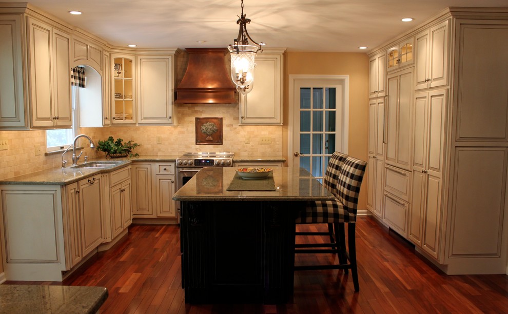 Bild på ett mellanstort vintage kök med öppen planlösning, med en undermonterad diskho, luckor med upphöjd panel, vita skåp, granitbänkskiva, beige stänkskydd, stänkskydd i stenkakel, integrerade vitvaror, mellanmörkt trägolv och en köksö
