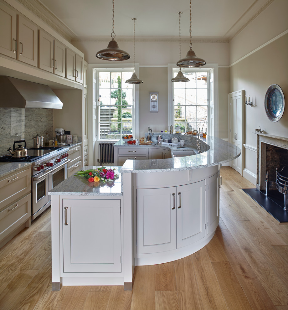 Inspiration for a large timeless galley light wood floor eat-in kitchen remodel in Wiltshire with shaker cabinets, gray cabinets, granite countertops, stainless steel appliances, an island, gray backsplash, a farmhouse sink and porcelain backsplash