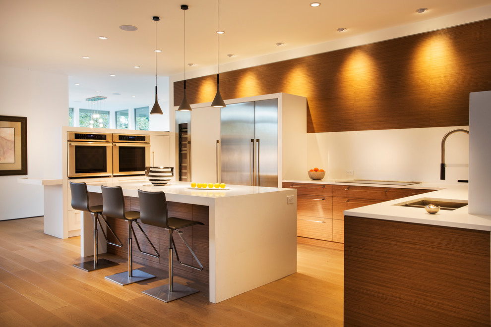 Foto di una cucina design con lavello sottopiano, ante lisce, ante in legno scuro, paraspruzzi bianco, elettrodomestici in acciaio inossidabile e pavimento in legno massello medio