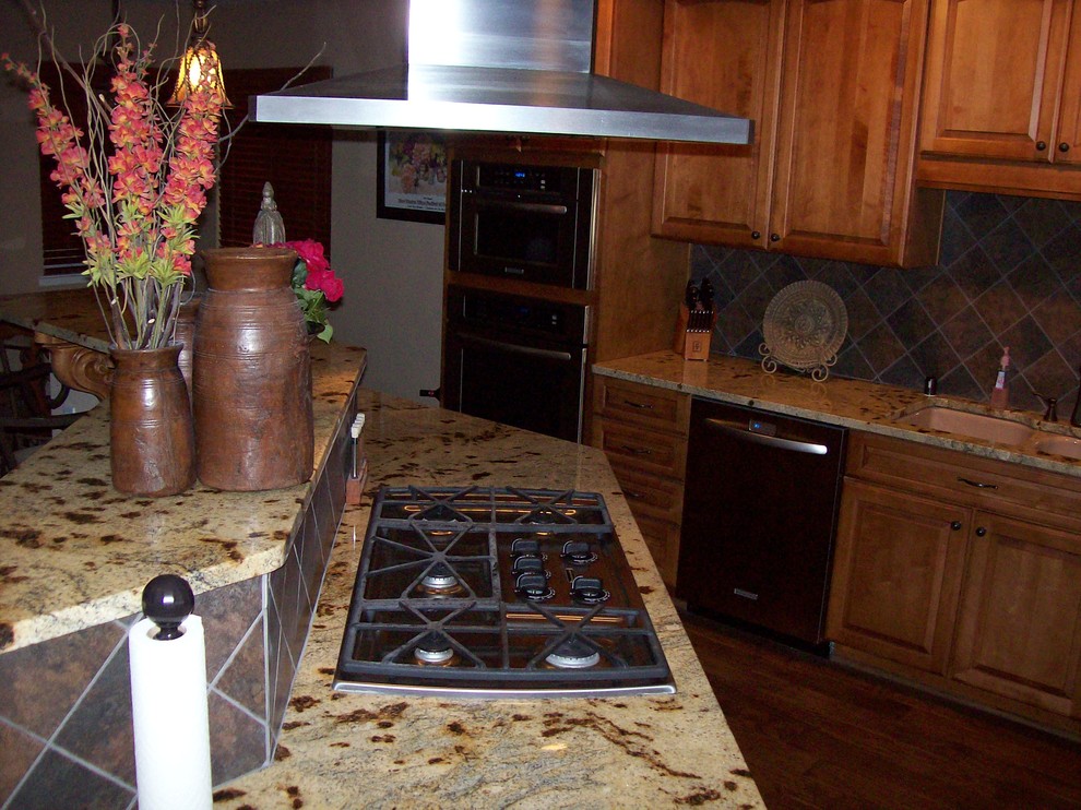На фото: кухня в стиле рустика с врезной мойкой, гранитной столешницей, фартуком из керамогранитной плитки и паркетным полом среднего тона