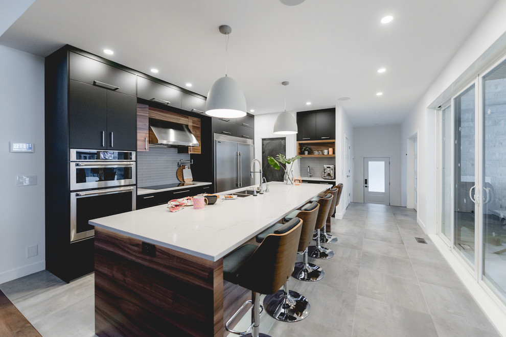 This is an example of a medium sized contemporary single-wall kitchen in Montreal with a submerged sink, flat-panel cabinets, black cabinets, engineered stone countertops, grey splashback, ceramic splashback, stainless steel appliances, ceramic flooring, an island and grey floors.