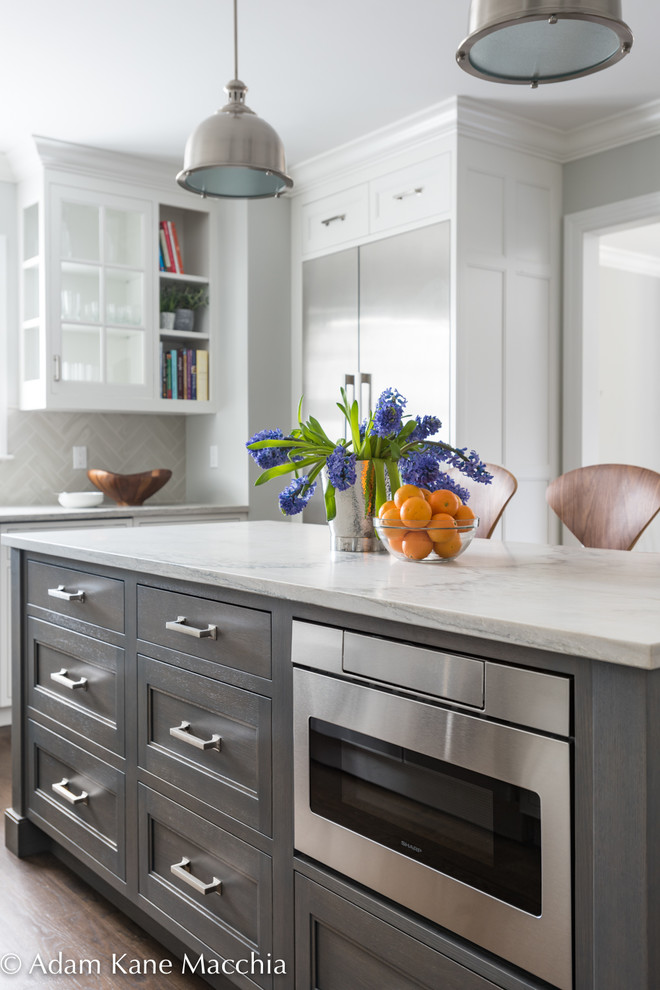 Inspiration for a mid-sized transitional l-shaped dark wood floor open concept kitchen remodel in New York with an undermount sink, shaker cabinets, white cabinets, quartzite countertops, gray backsplash, ceramic backsplash, stainless steel appliances and an island